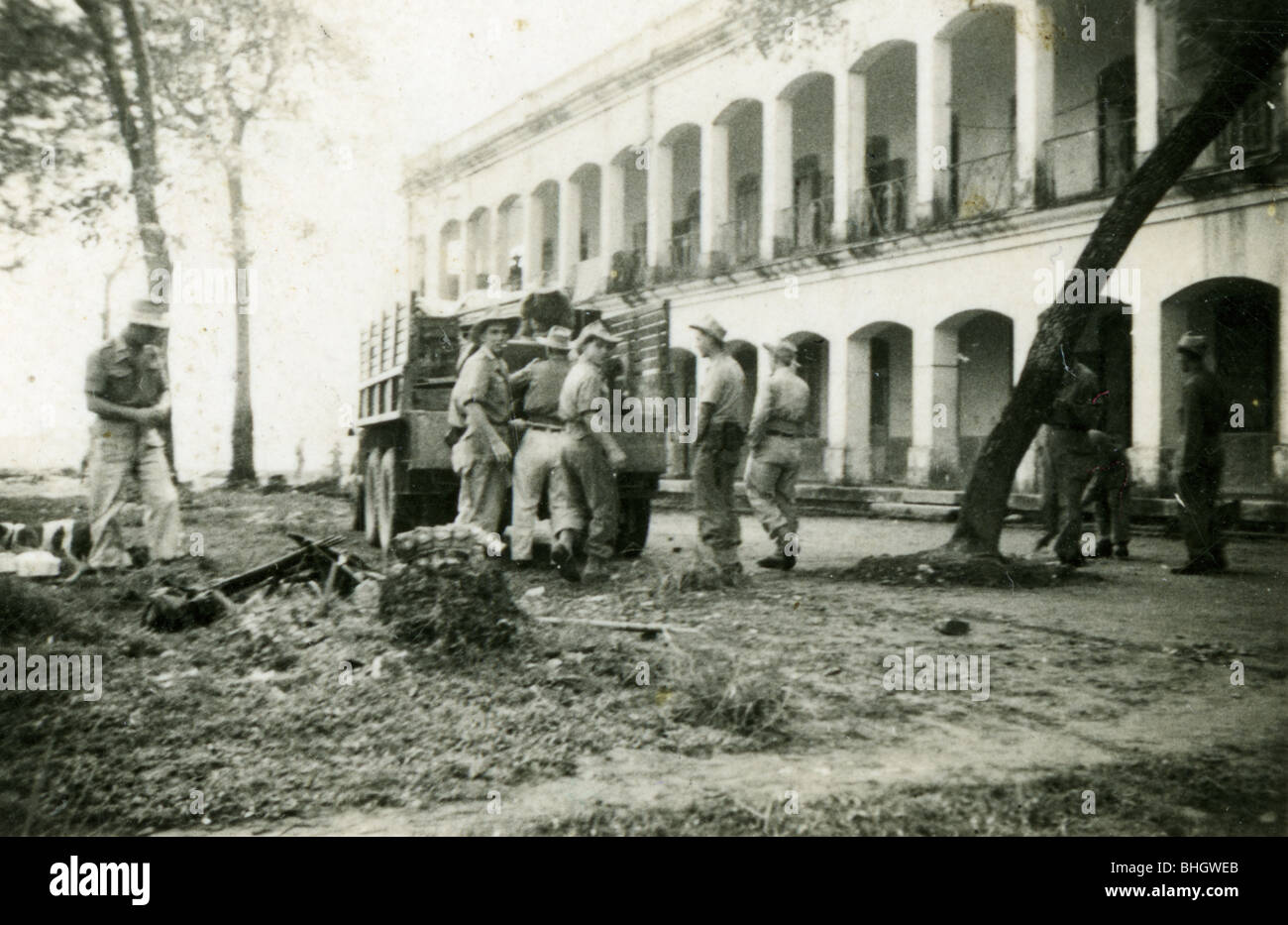 Members of the French Foreign legion unload a truck near a colonial style building. architecture. horizontal black and white Stock Photo