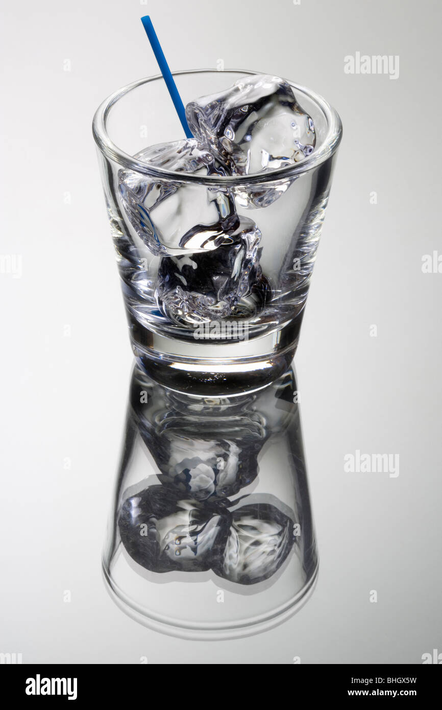 Empty mixed drink tumbler with ice on gray background with relfection