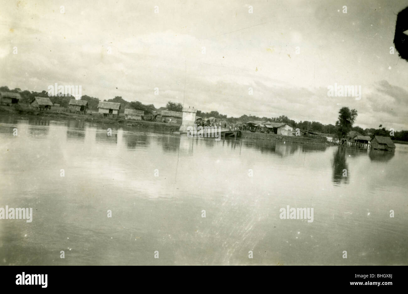 A vietnamese village on stilts and made of straw is seen from a river