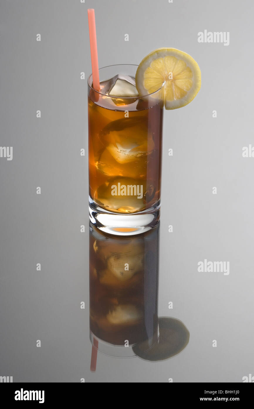 Long Island Iced Tea mixed drink with lemon slice garnish on grey