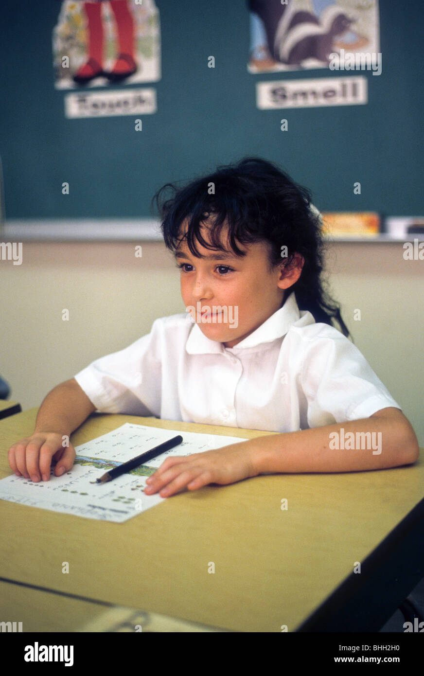 young girl smile desk school alert listen wait write test Stock Photo
