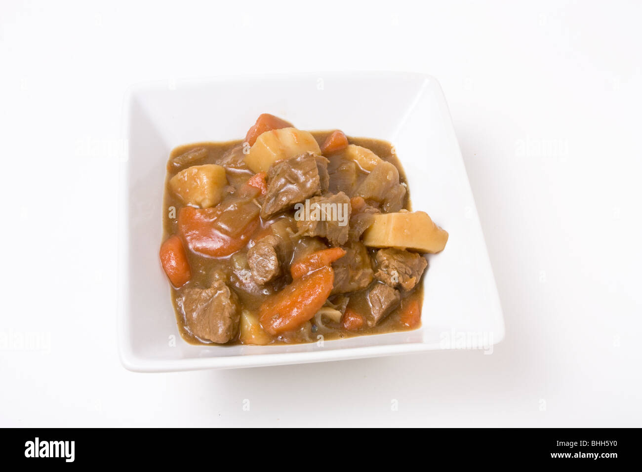 Beef stew or Goulash in white bowl isolated against white background. Stock Photo