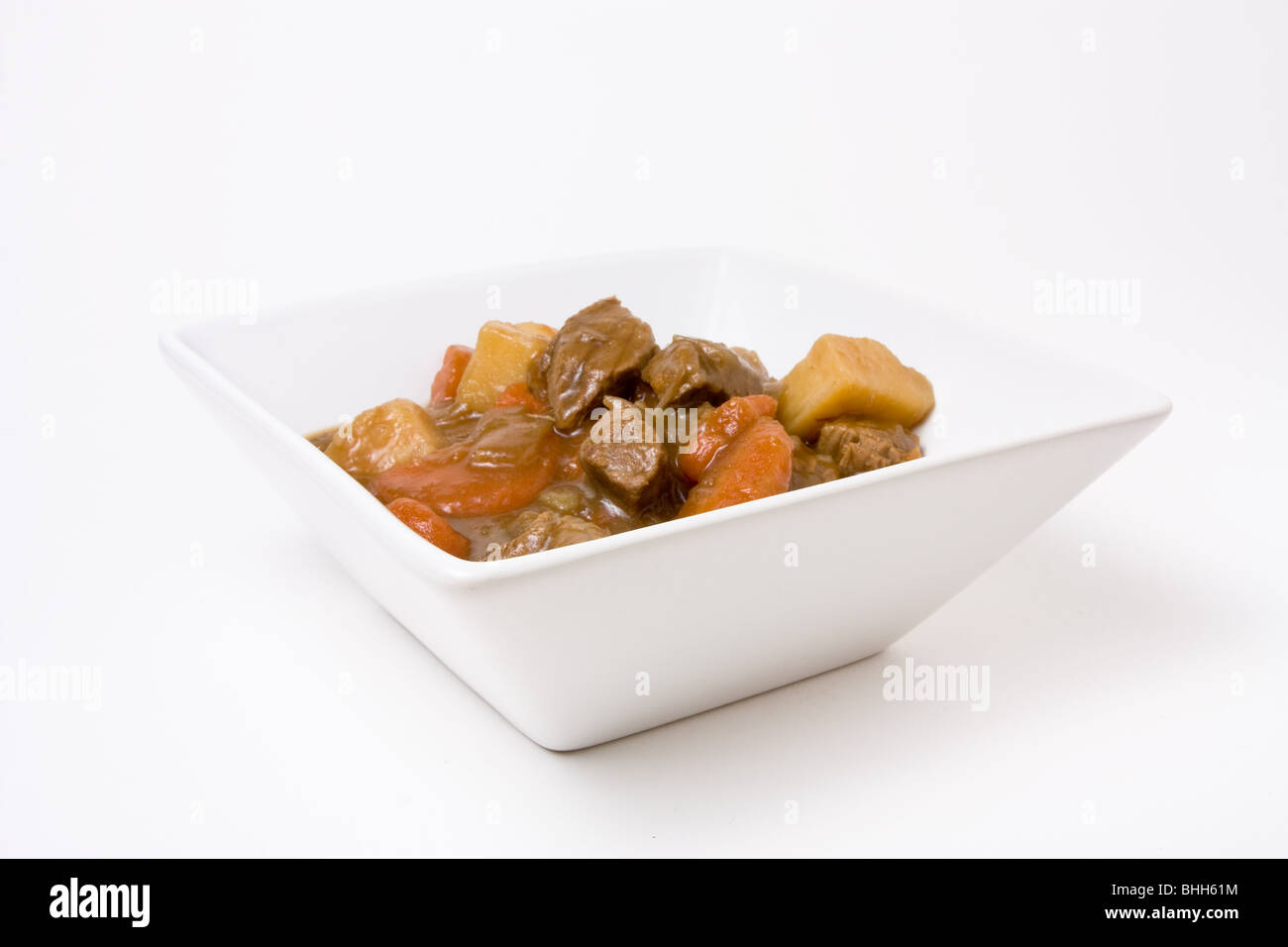 Beef stew or Goulash in white bowl isolated against white background. Stock Photo