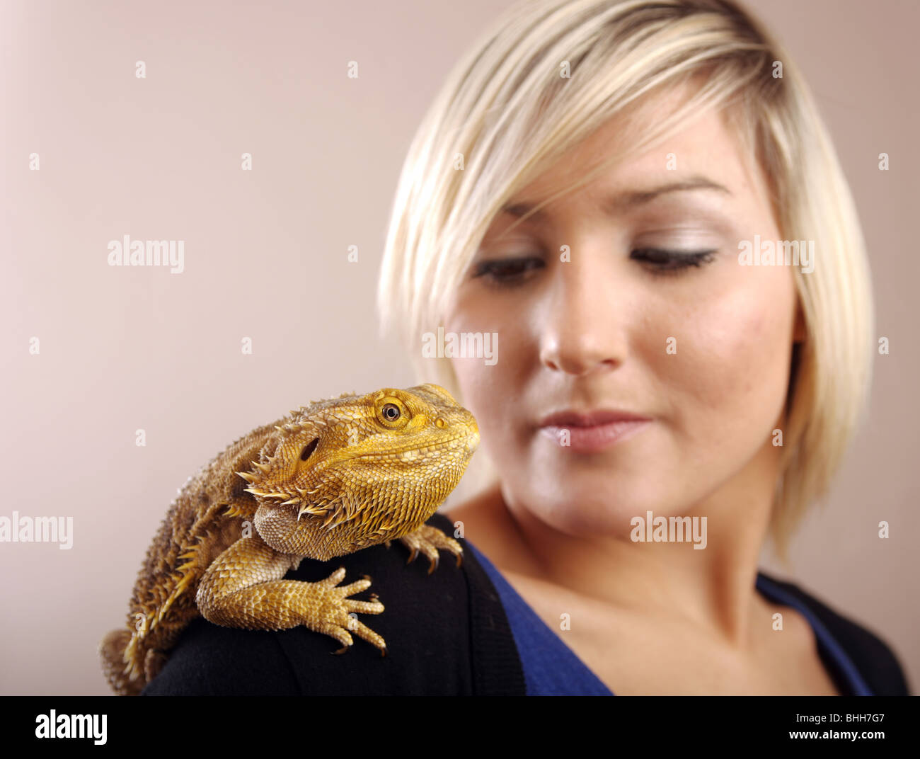 A blonde haired woman with a Bearded Dragon sitting on her shoulder