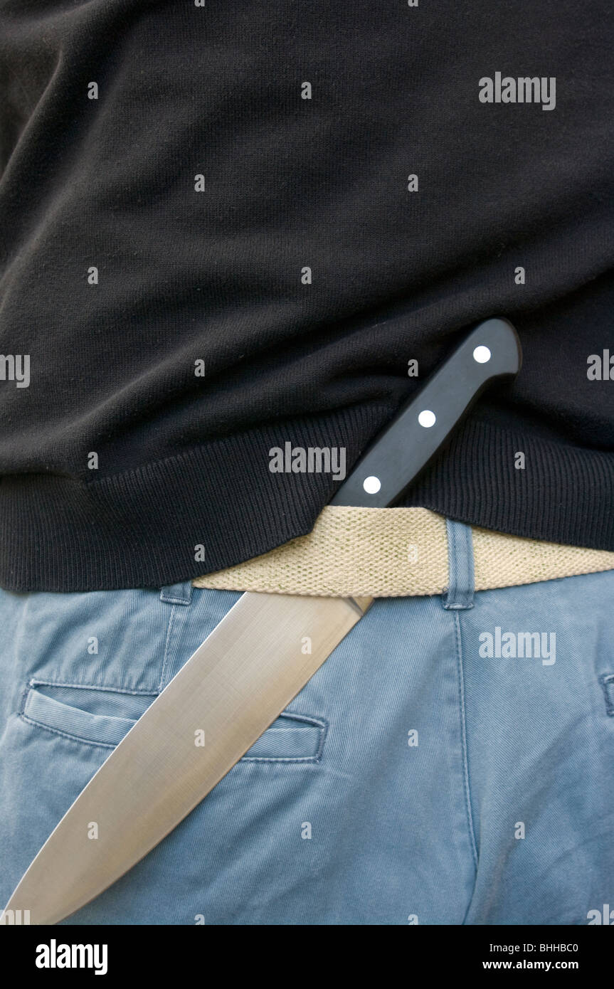 Kitchen Knife Tucked In The Rear Of A Trouser Belt Stock Photo
