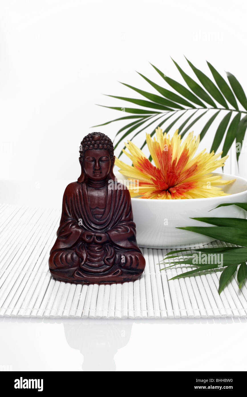 Buddhafigur vor Porzellanschale mit Chrysantheme Stock Photo