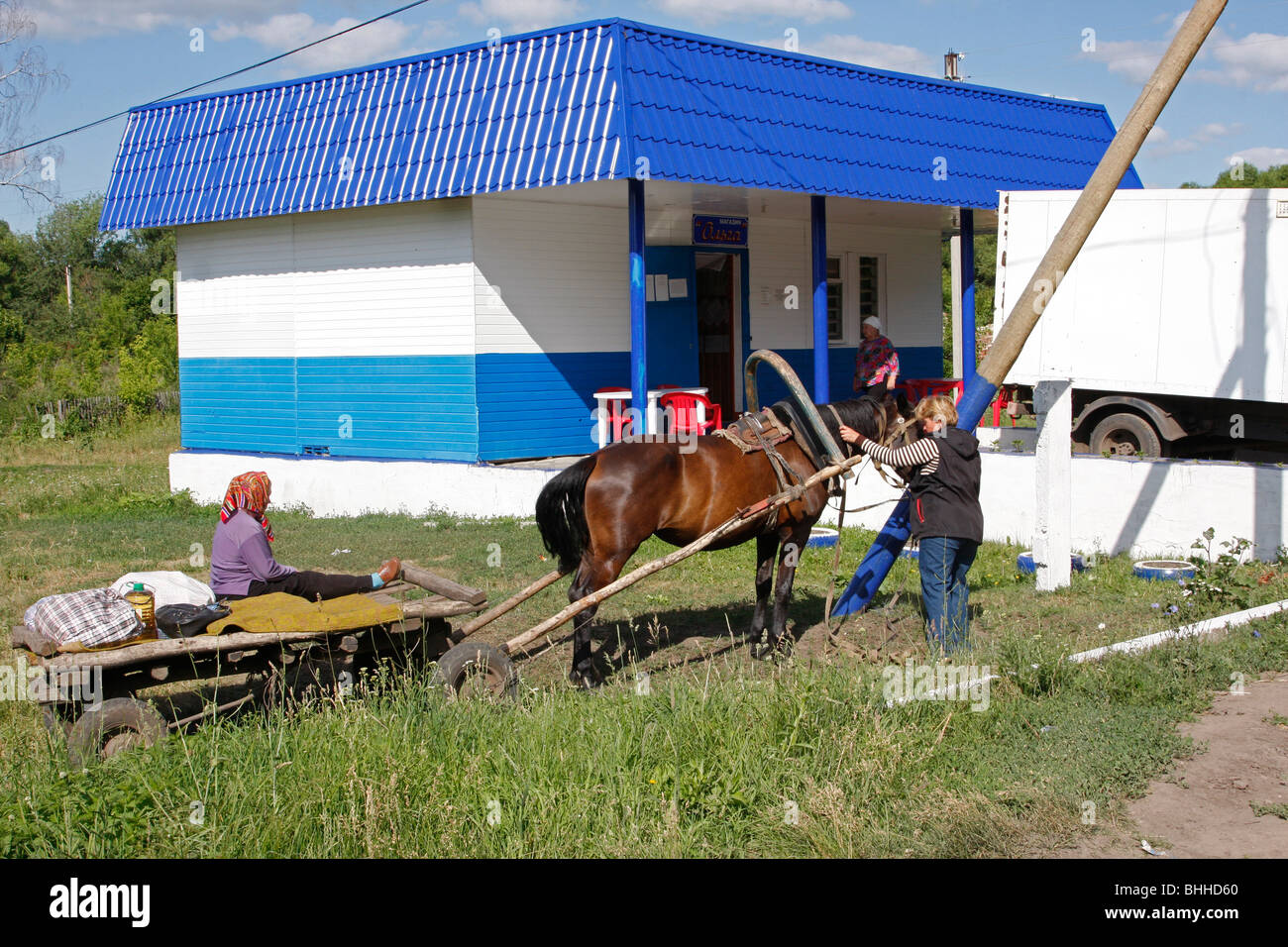A couple of Russian women came on horse driven cart to buy products in the village shop. Stock Photo