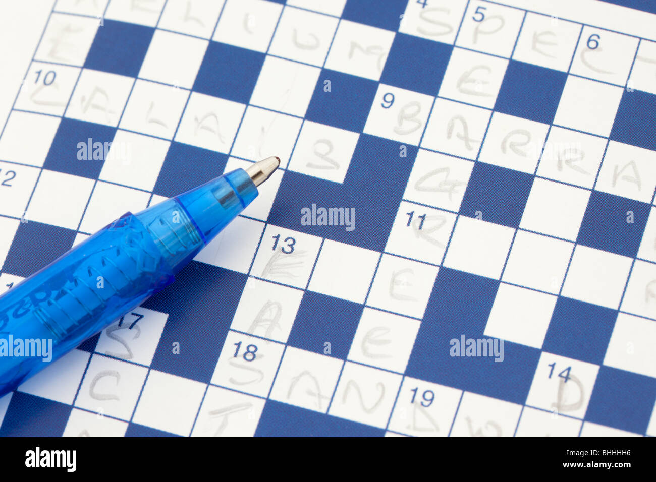 Studio still life UK Europe. Close-up of an incomplete blue and white paper crossword puzzle with a blue ballpoint pen Stock Photo