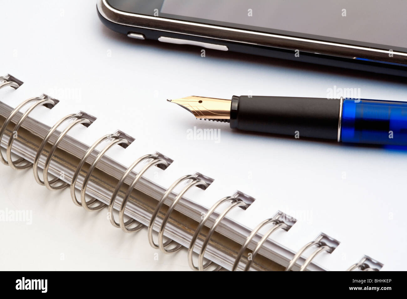 closeup of a fountain pen, spiral notebook and cell phone Stock Photo