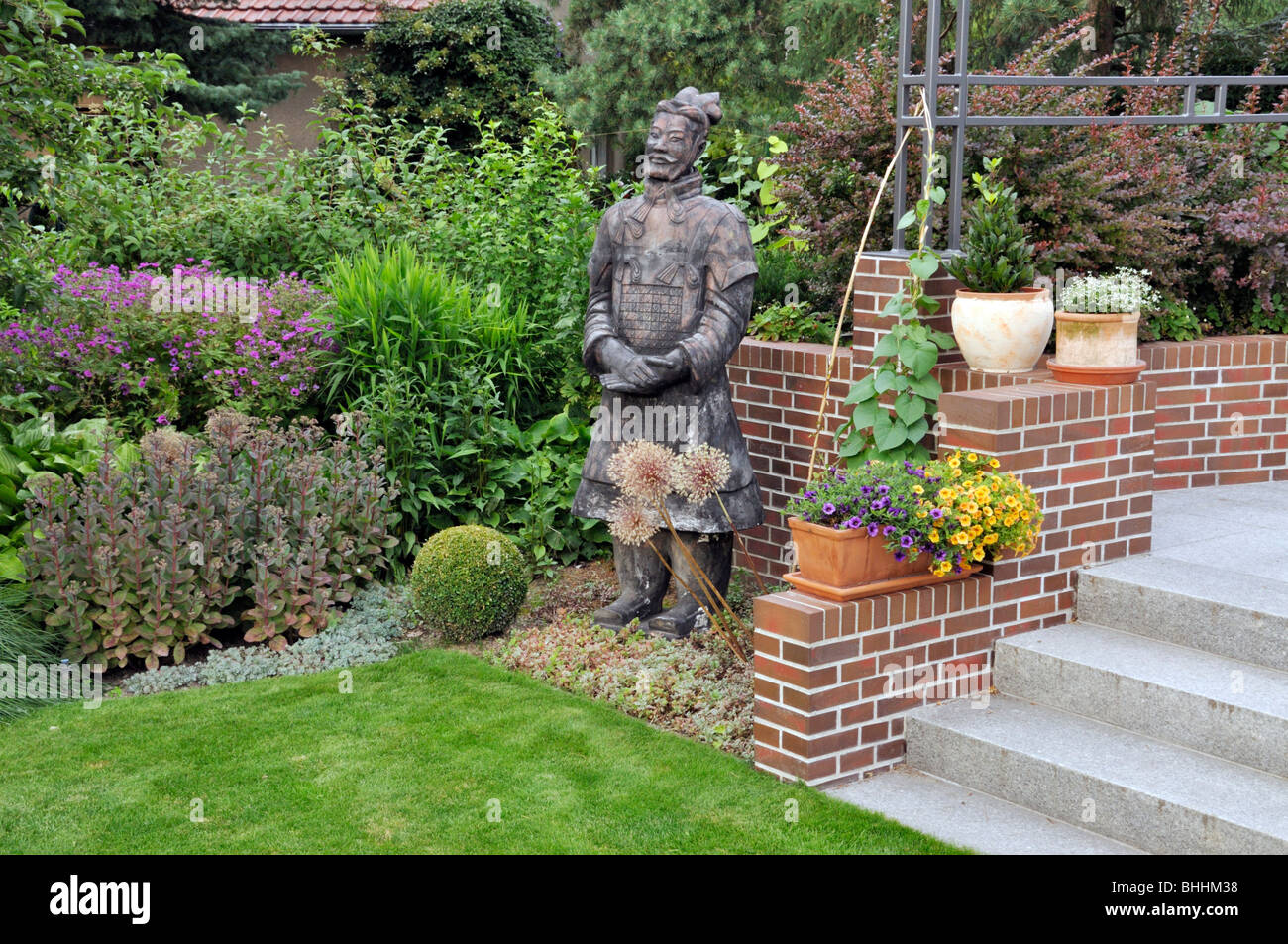Perennial border with potted plants and reproduction of a Chinese clay warrior Stock Photo