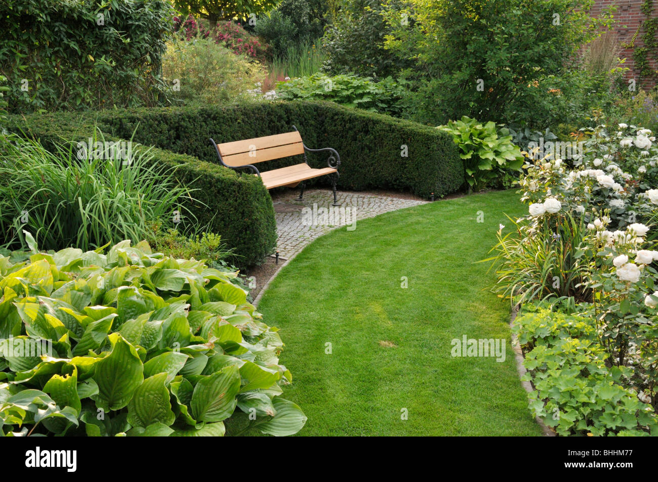 Grass path in a perennial garden with bench Stock Photo