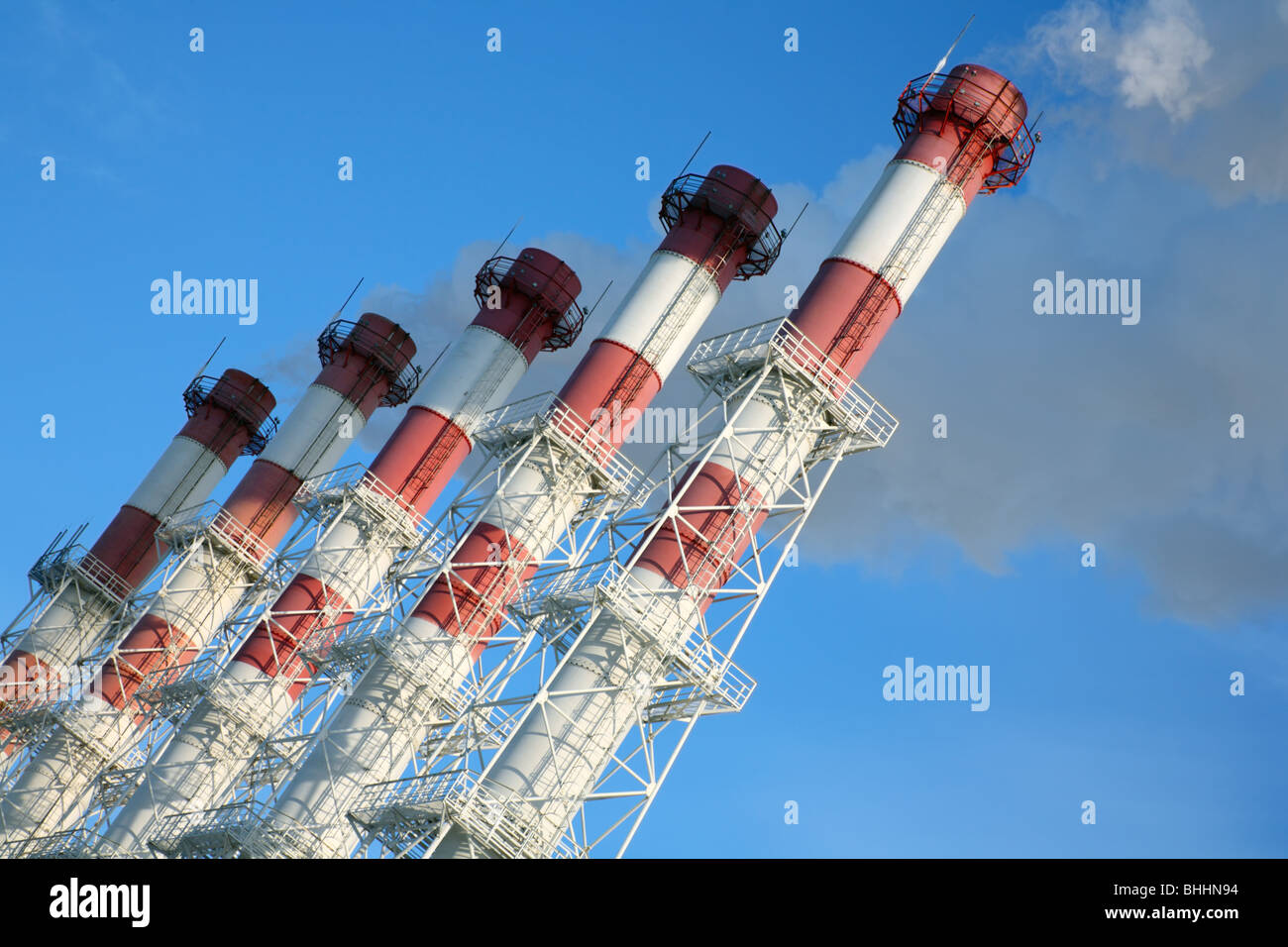Five chimneys with steam on a blue sky background. Tilt view. Stock Photo