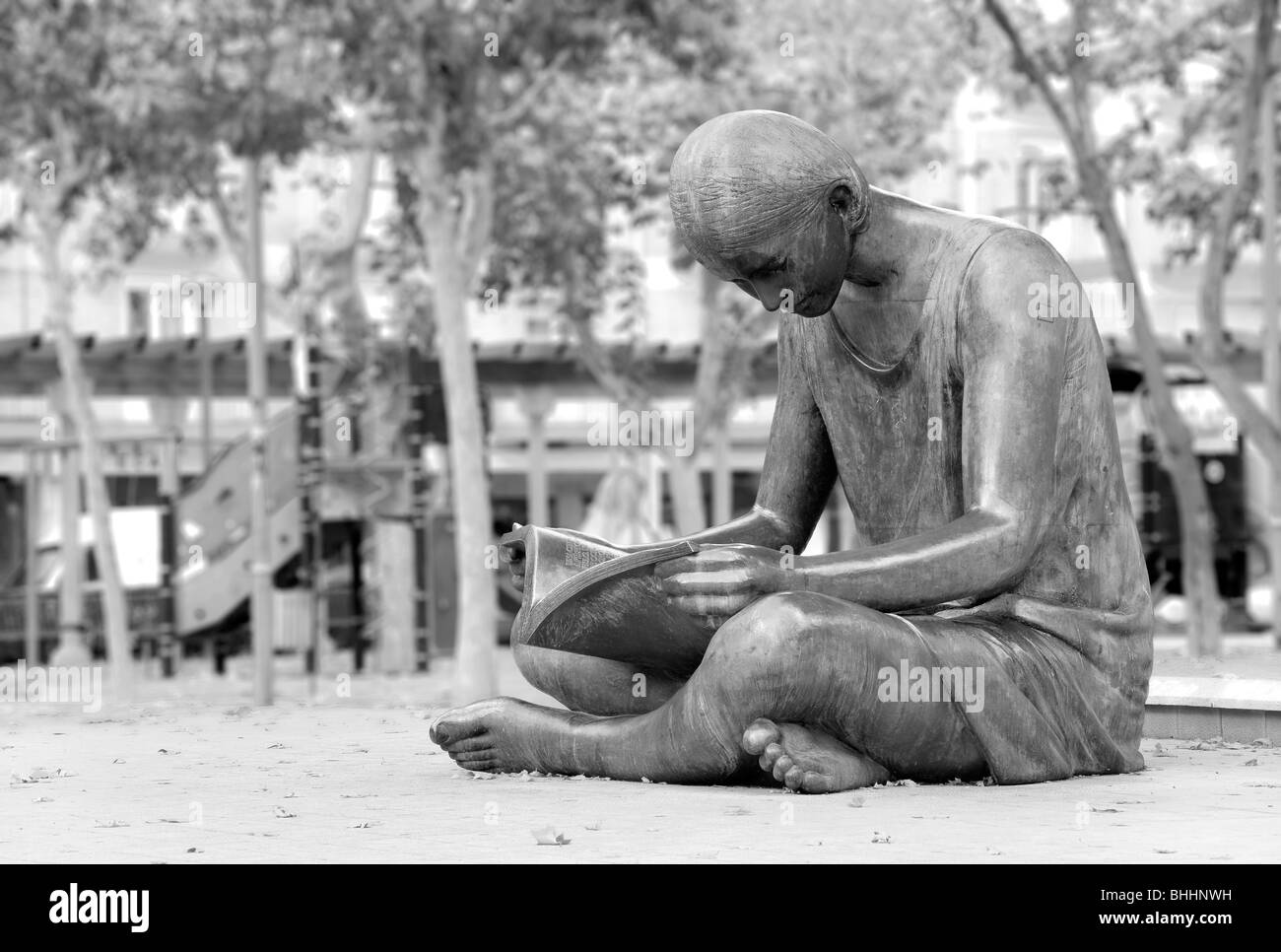 Woman in a dress sitting on the floor reading in the Plaza de las Batallas in Valladolid, Spain Stock Photo