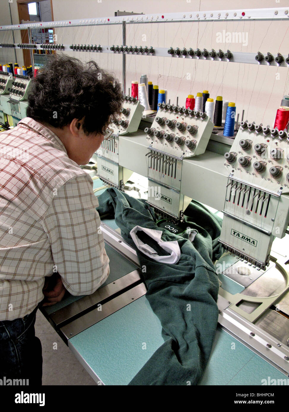 A computer-programmed automatic embroidery machine stitches a monogram on a shirt in Laguna Niguel, CA. Stock Photo