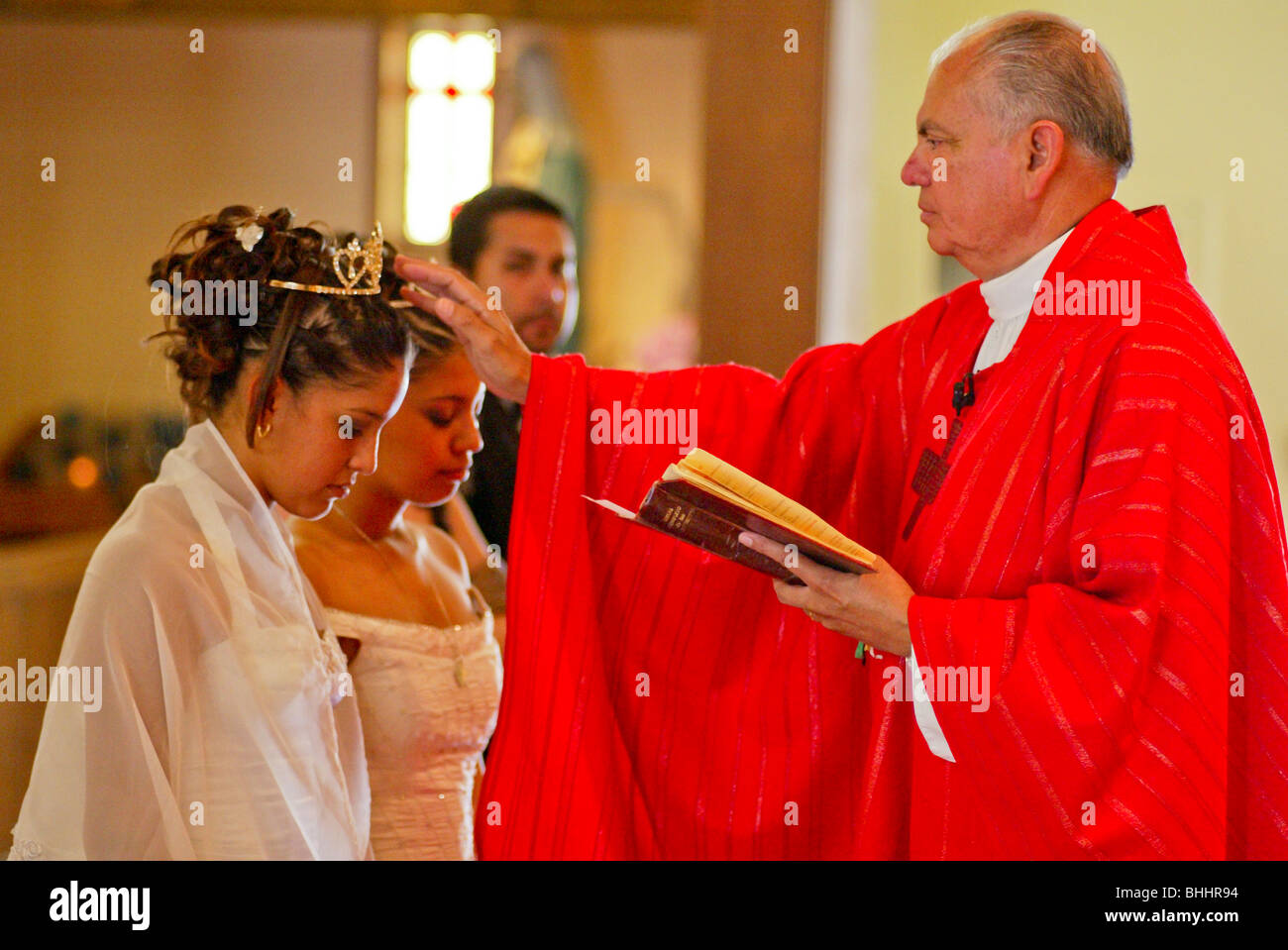 Formally Dressed Hispanic Twin Sisters Before A Priest At Their