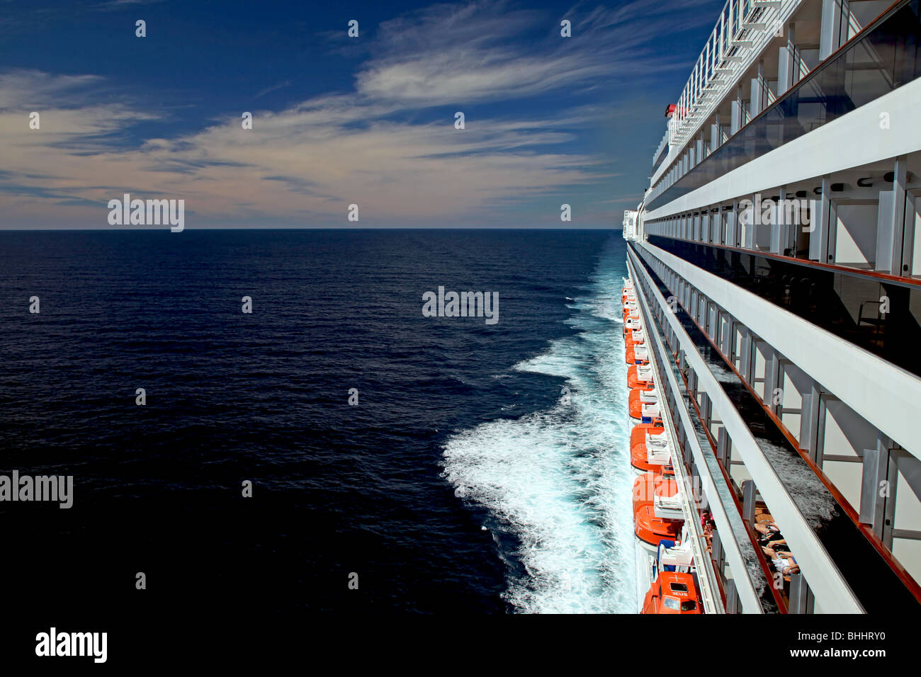 Cruise ship passengers on balconies, lifeboats, and ocean wake looking ...