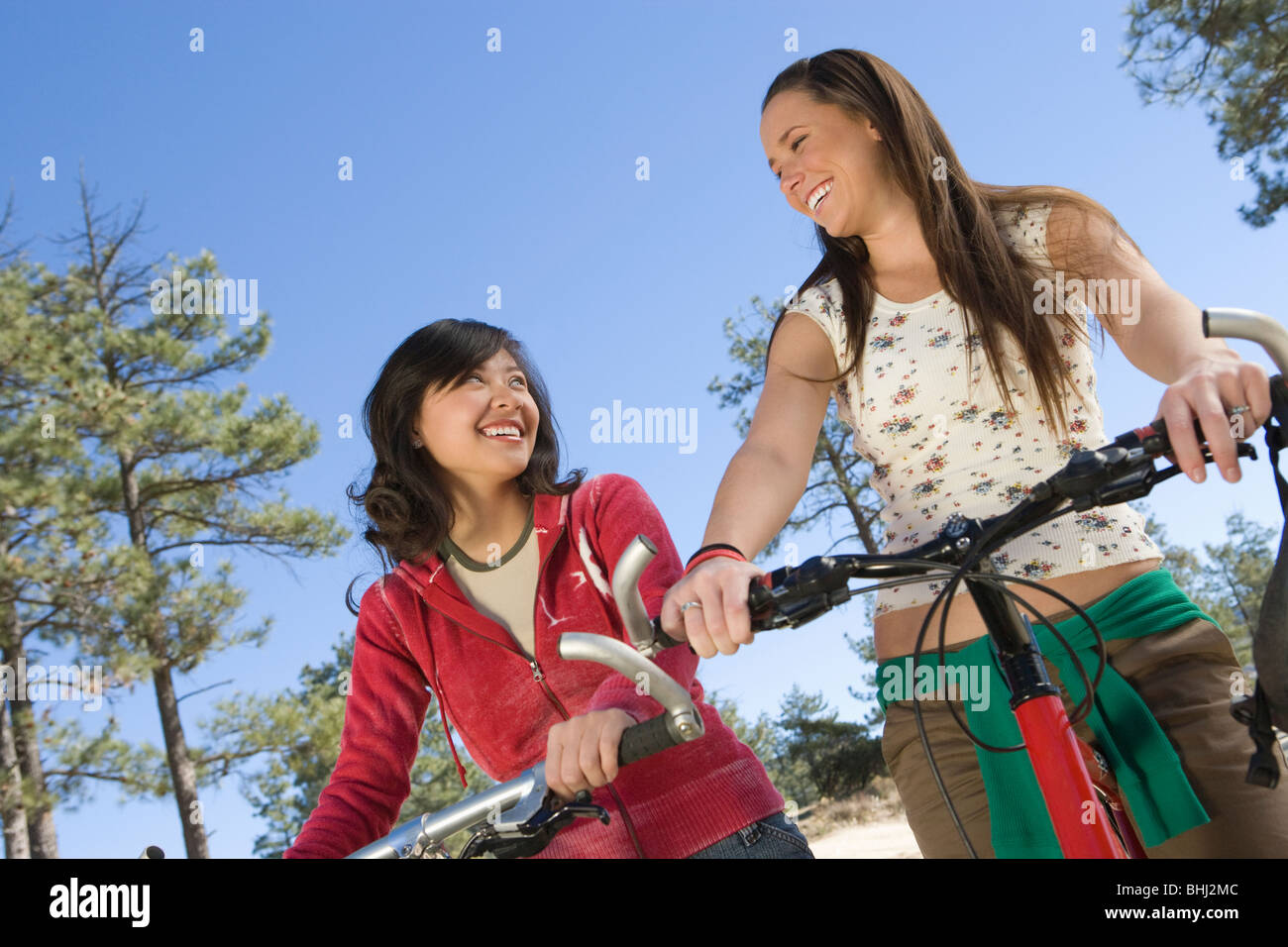Two women stand smiling with mountain bikes Stock Photo