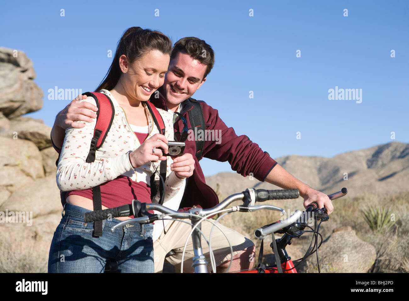 Young couple with mountain bikes stand looking at camera Stock Photo
