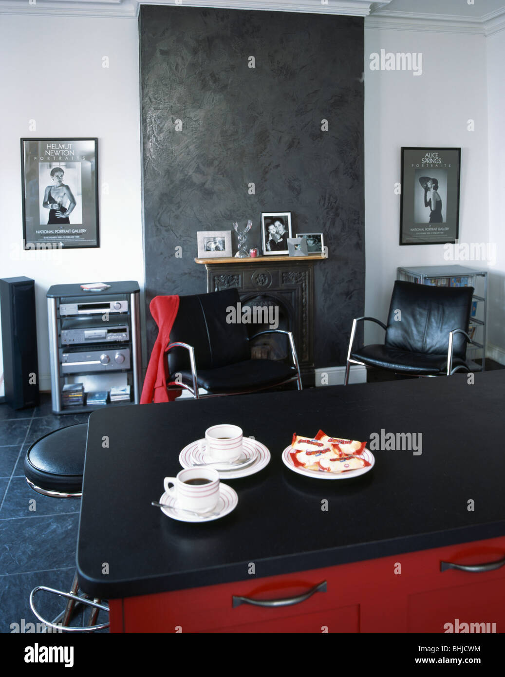 White cups on black granite worktop in modern kitchen with slate panel above fireplace Stock Photo