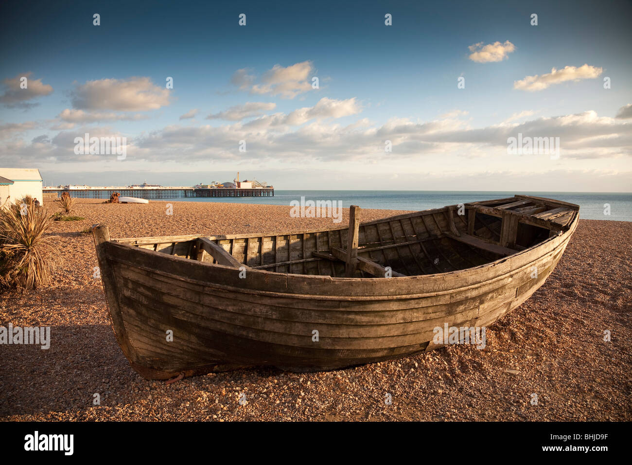 Beached rowing boat, Brighton pebble beach with Brighton (East) Pier in the background, evening sunlight Stock Photo