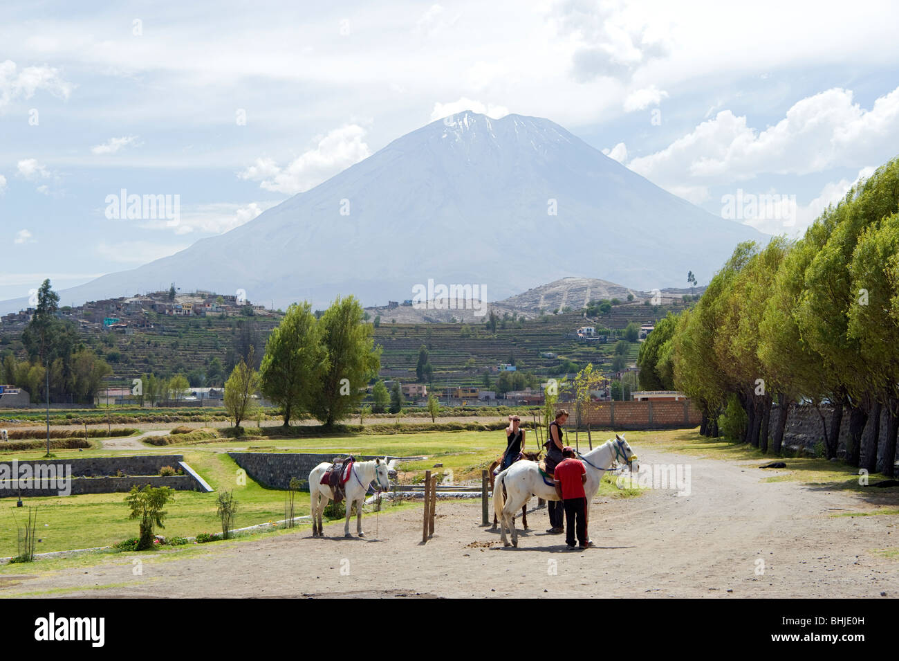 Tourists about to set off on a horse ride with a backdrop of a snow-capped volcano at Arequipa, Peru Stock Photo