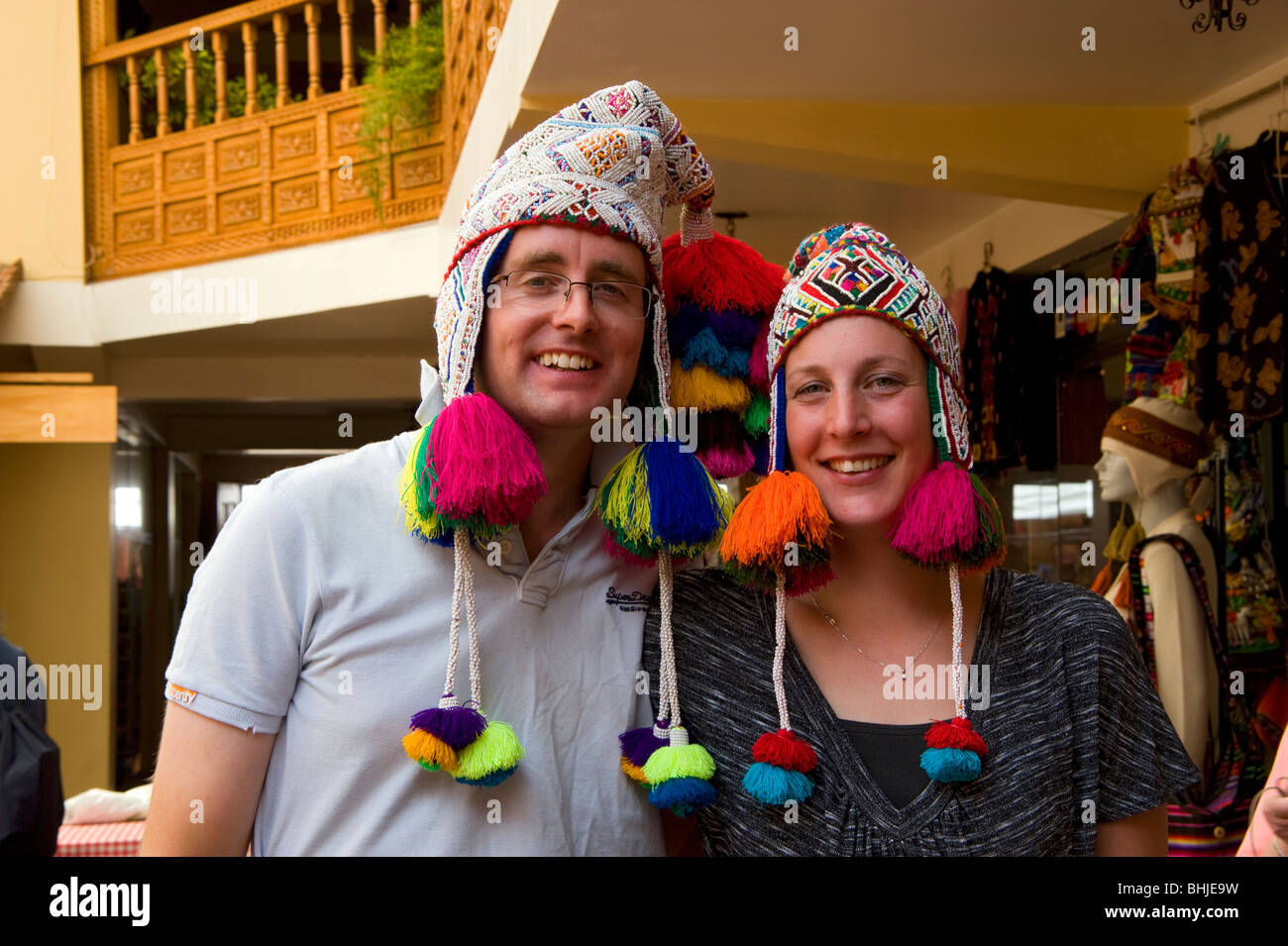 A young couple trying on Peruvian hats at the Pisac market, Peru Stock Photo