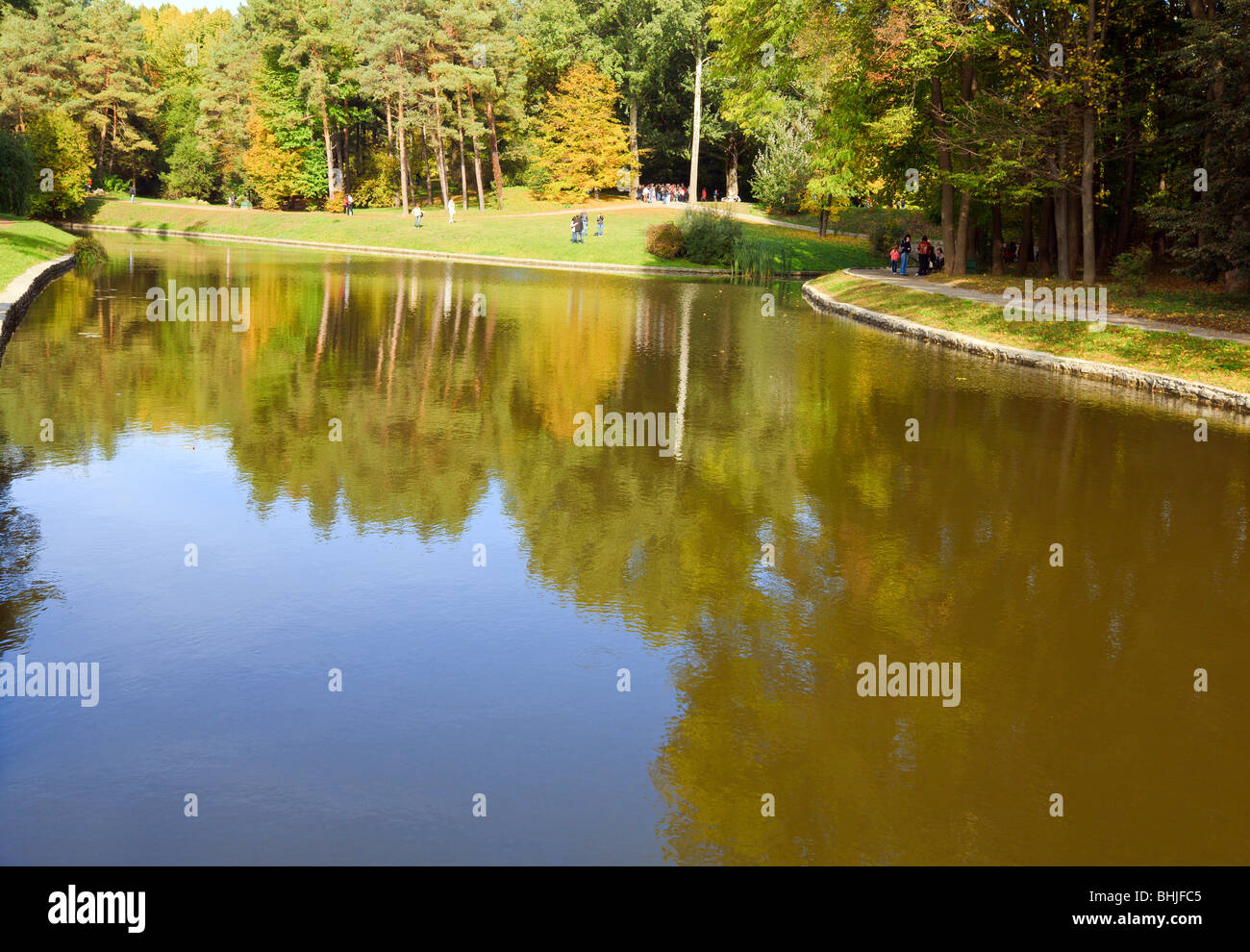 Pond water surface with reflection of colorful trees and walkway in ...
