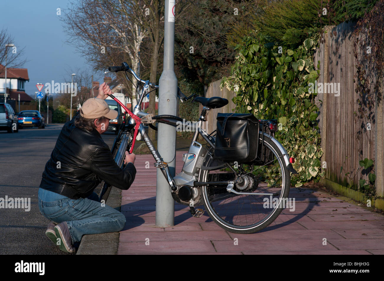 Bicycle thief takes wire cutters to steal chained up bike Stock Photo