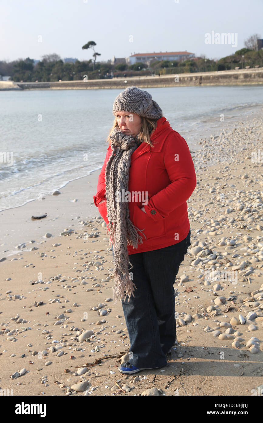 Plump woman walking on wintery beach Stock Photo