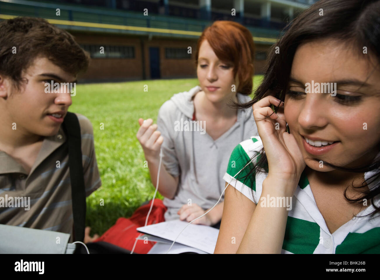 Teenage friends hanging out, girls sharing earphones, listening to music Stock Photo