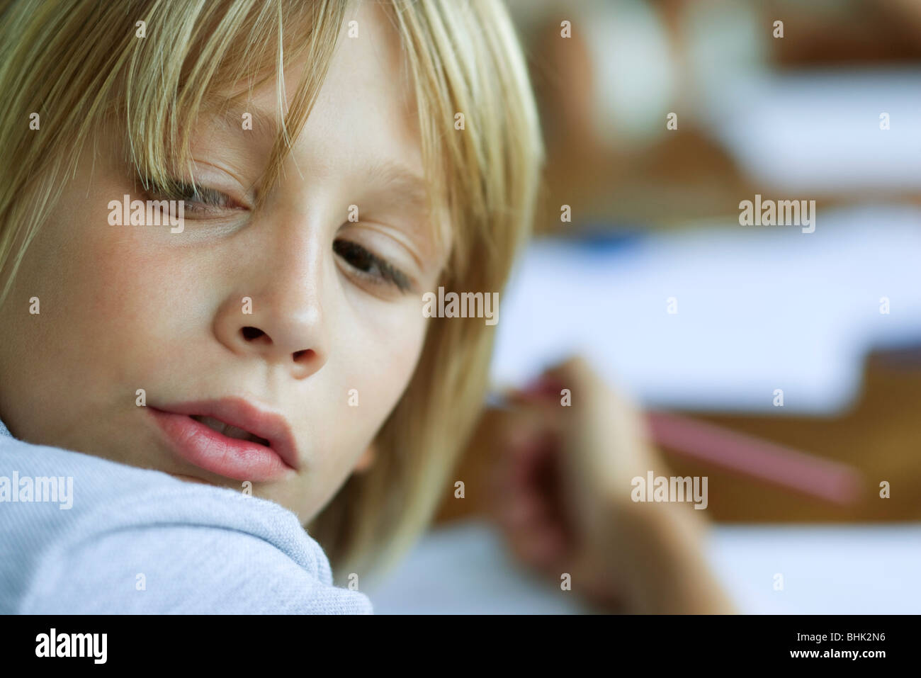 Boy looking over shoulder, distracted from work Stock Photo