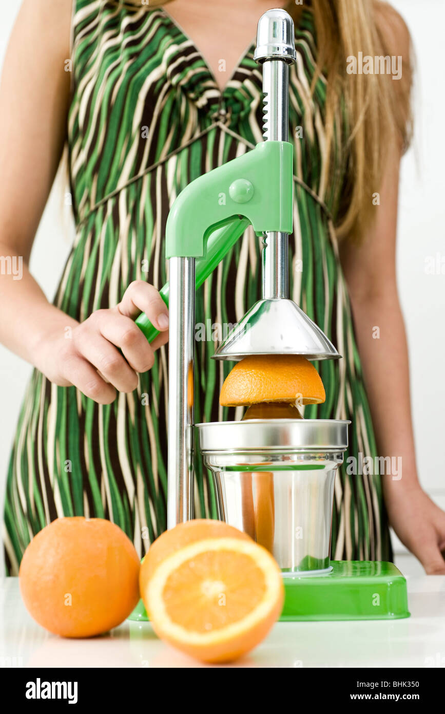 Using press to squeeze fresh orange juice Stock Photo