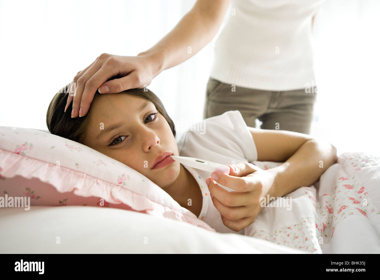 Girl checking temperature with thermometer, mother caressing forehead Stock Photo Alamy