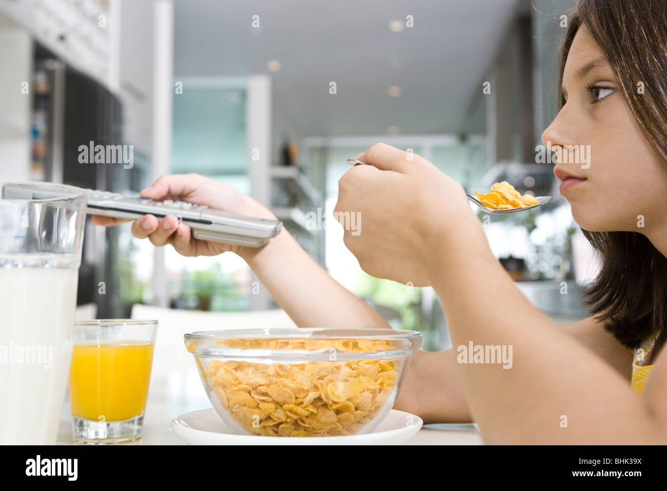 Girl watching television while eating breakfast Stock Photo Alamy