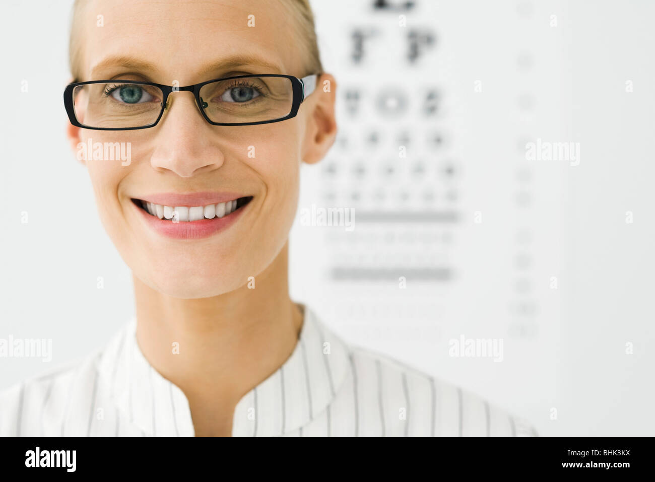 Young woman wearing glasses, eye chart in background, portrait Stock Photo