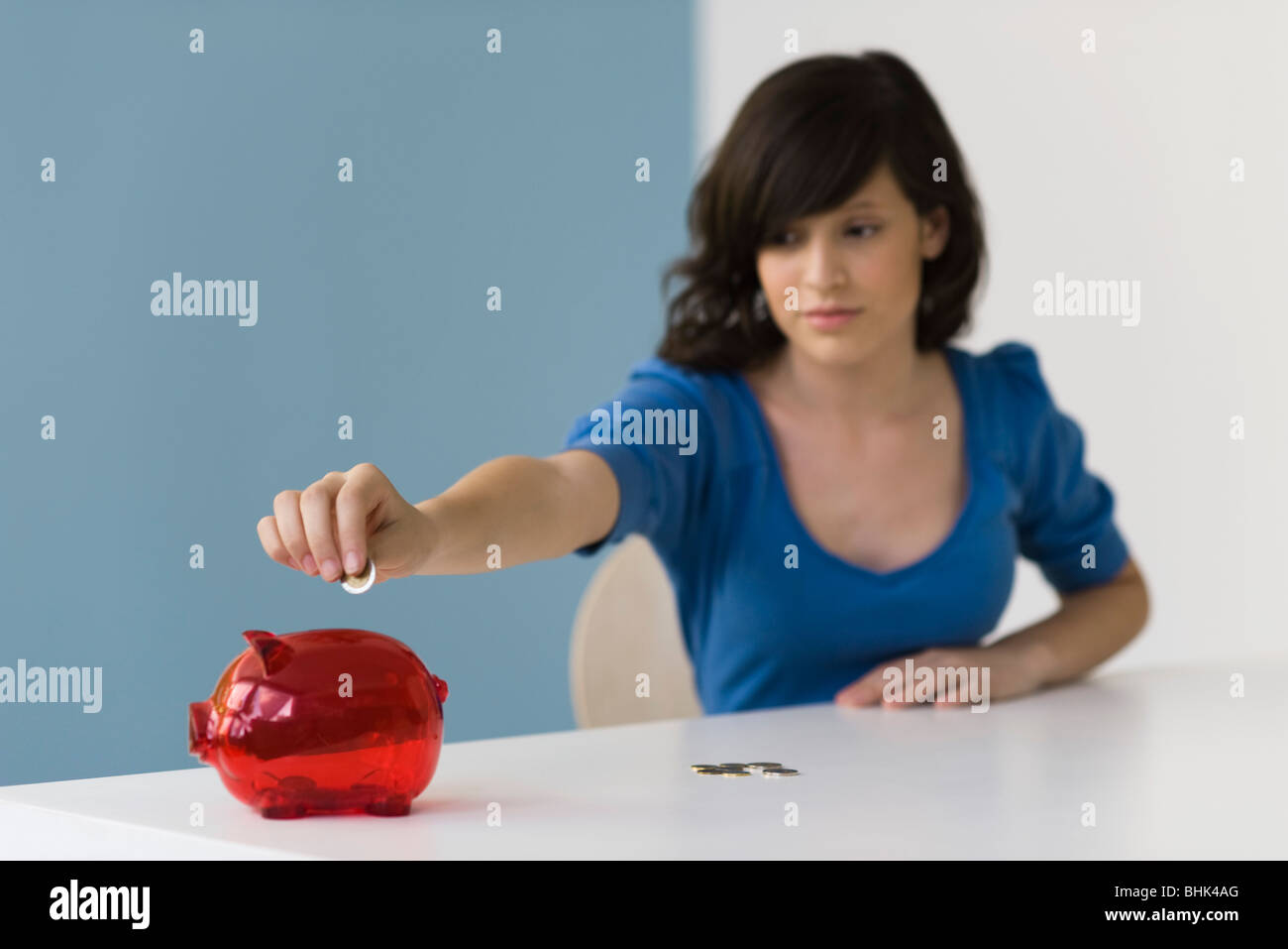 Teenage girl putting coin in piggy bank Stock Photo