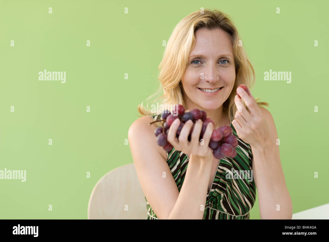 Mature woman eating grapes Stock Photo