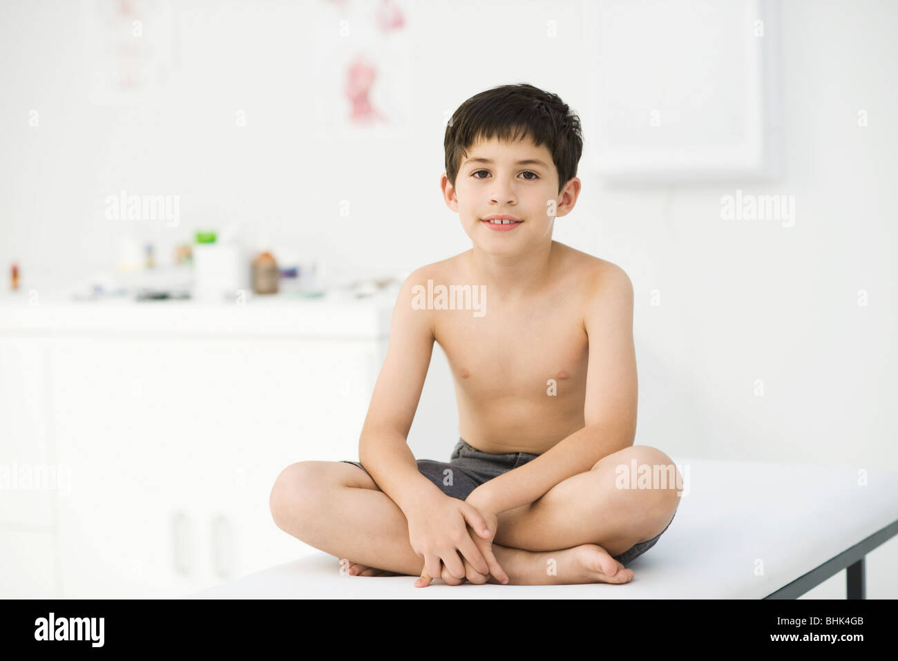 Boy sitting on examining table in doctor's office Stock Photo