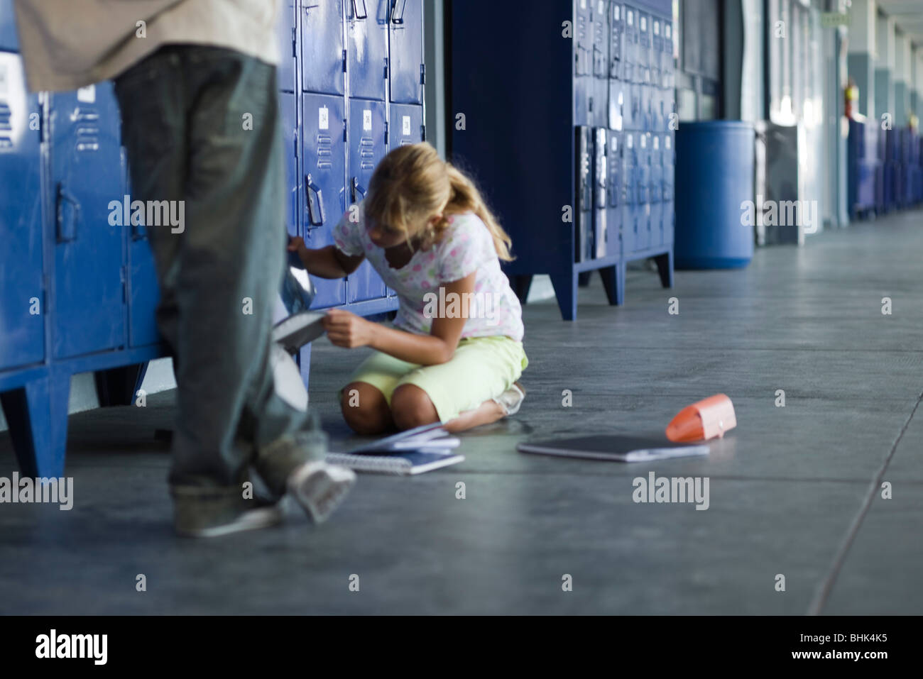 Junior high student picking up dropped school supplies, boy standing by watching Stock Photo
