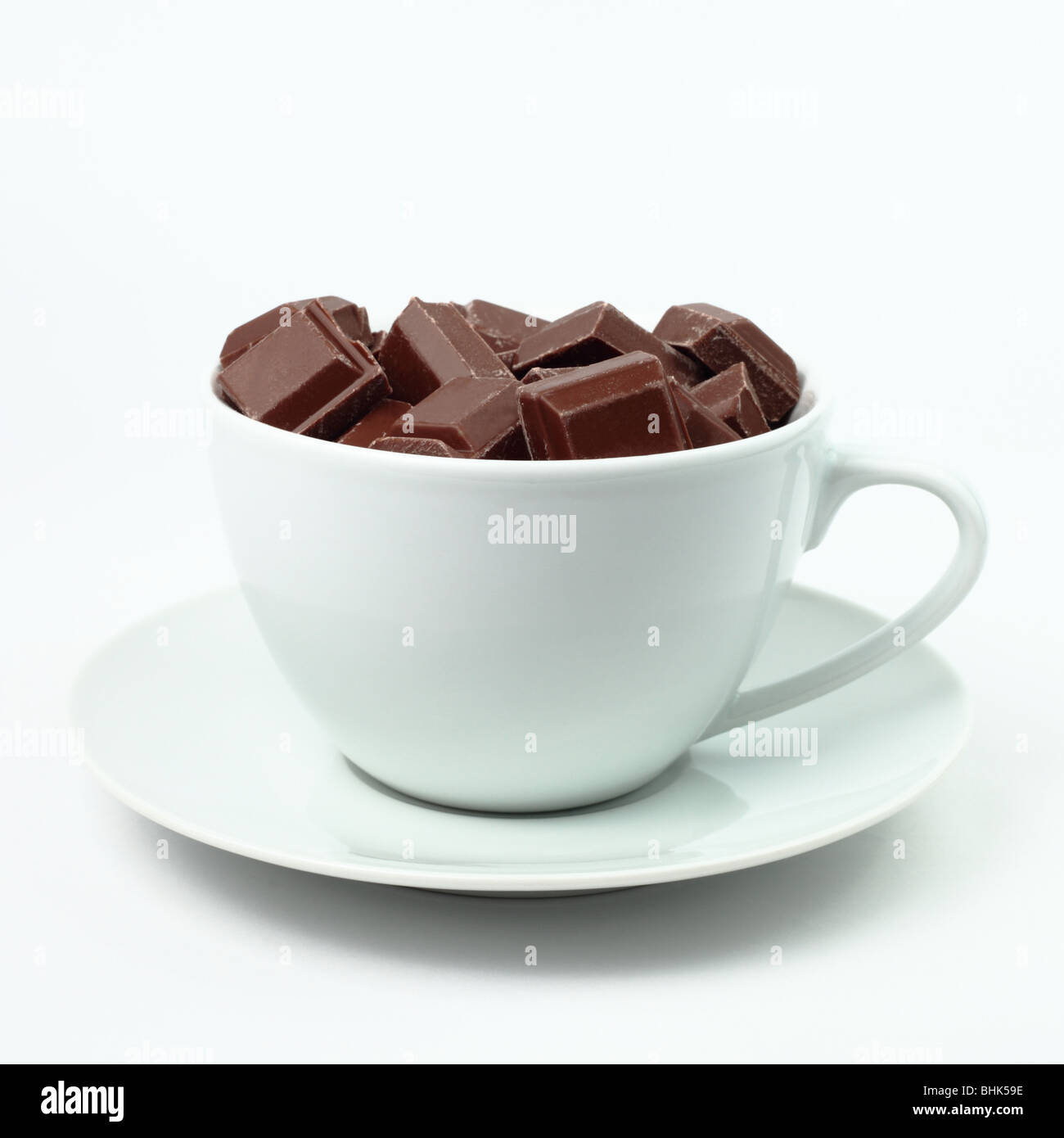 Cup full of milk chocolate pieces on a white background in a square format Stock Photo