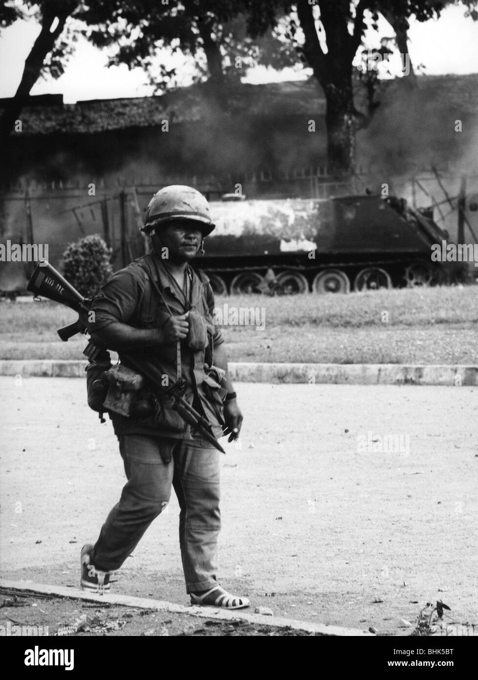 events, Vietnam War, Cambodian soldier in front of a burning military vehicle at Phnom Penh, Cambodia, after a Viet Cong attack, 7.10.1972, South-East Asia, Southeast Asia, Second Indochina War, 20th century, historic, historical, 1970s, 70s, US M113 armored personnel carrier, M 113, M-113, destroyed, wreck, weapon, arm, assault rifle, bayonet, uniform, uniforms, steel helmet, people, Stock Photo