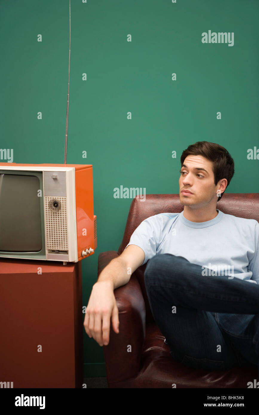 Man sitting in chair, looking away impatiently Stock Photo
