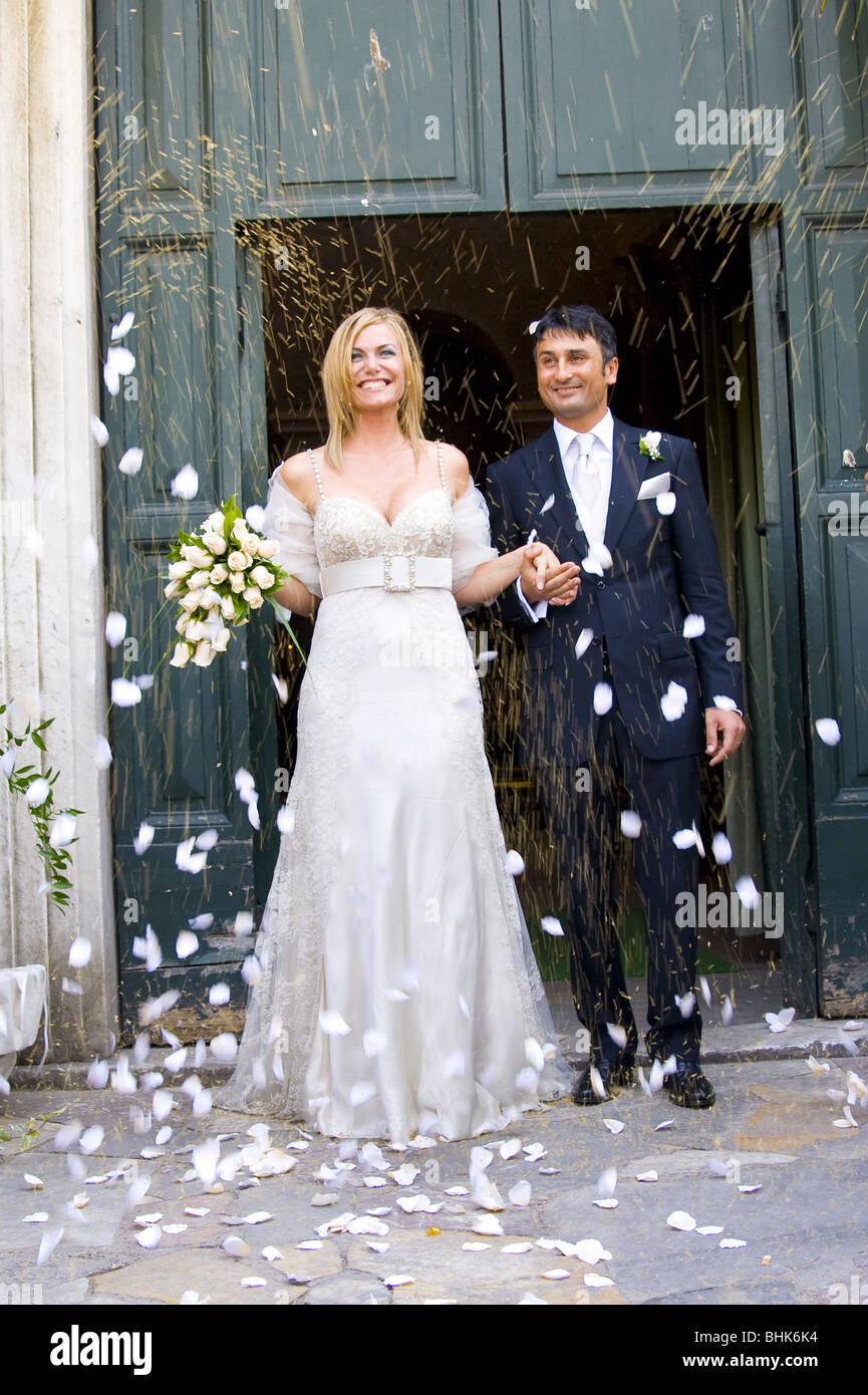 Newlyweds during rice and petal throwing after wedding ceremony Stock