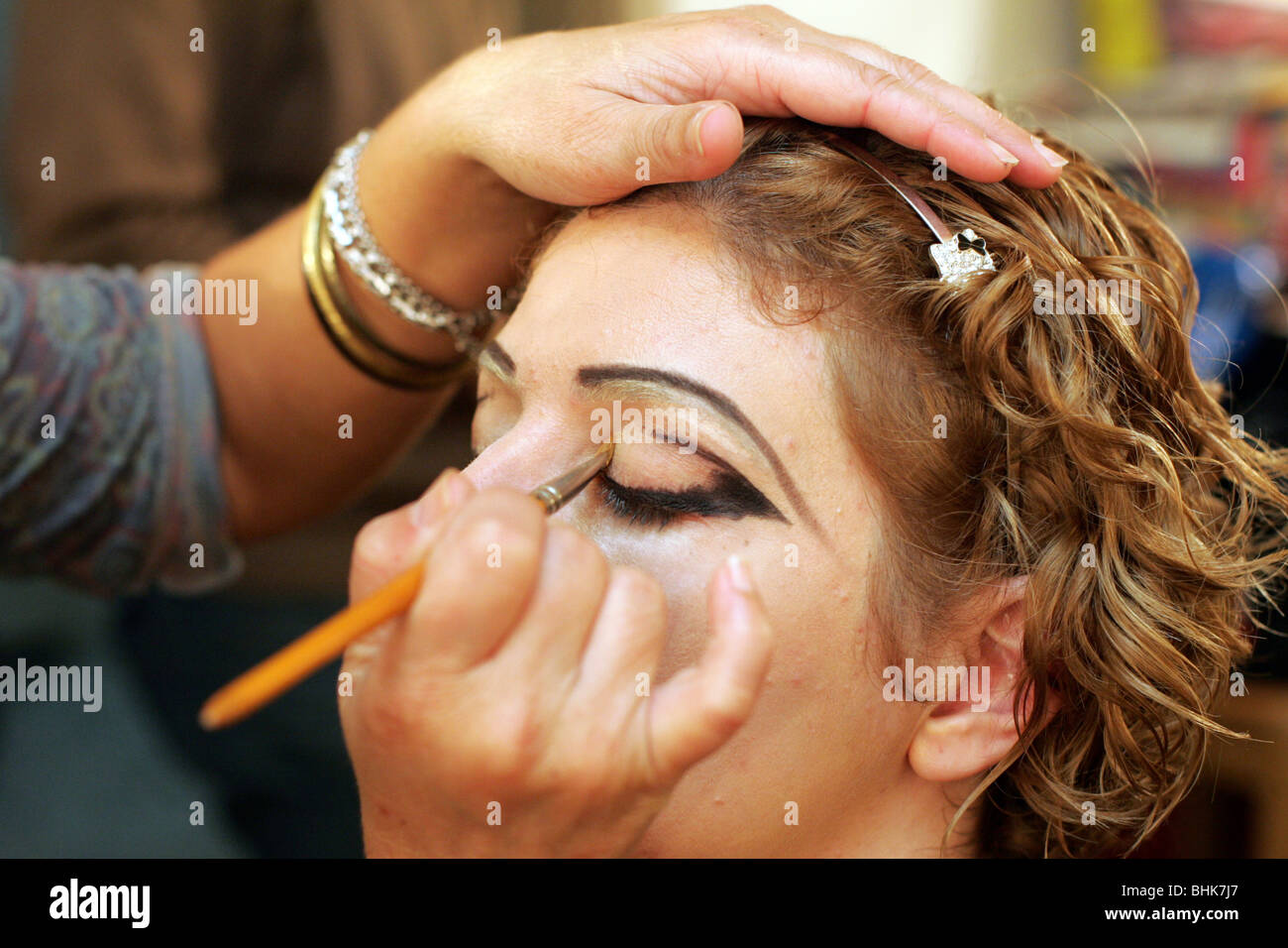 Makeup artist applying eyeliner to an actress. Stock Photo