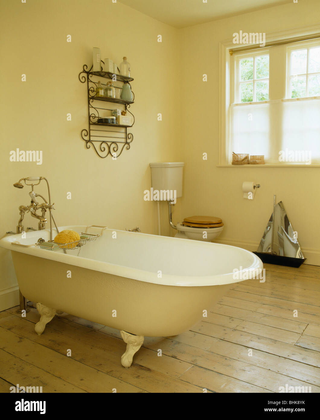 Rolltop bath in cream country bathroom with wooden flooring Stock