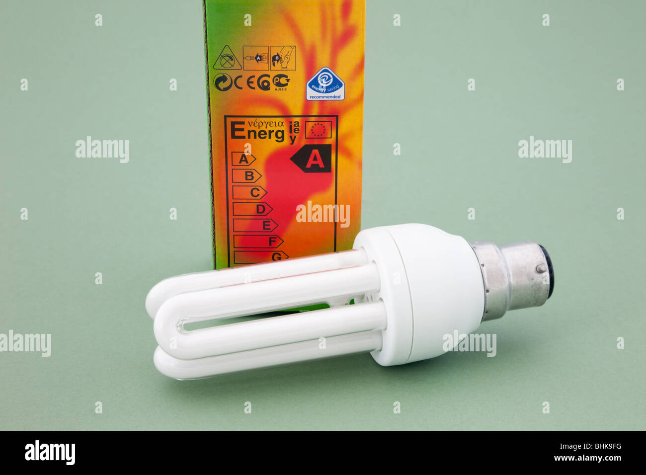 Studio UK Europe. Long life low energy light bulb and box with energy rating label on a green background Stock Photo