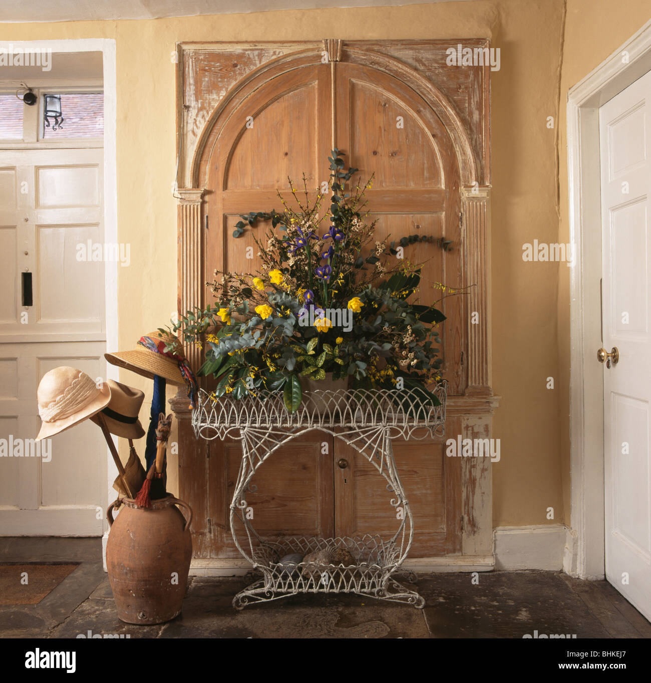 Flower arrangement on metal console table in front of old wooden door