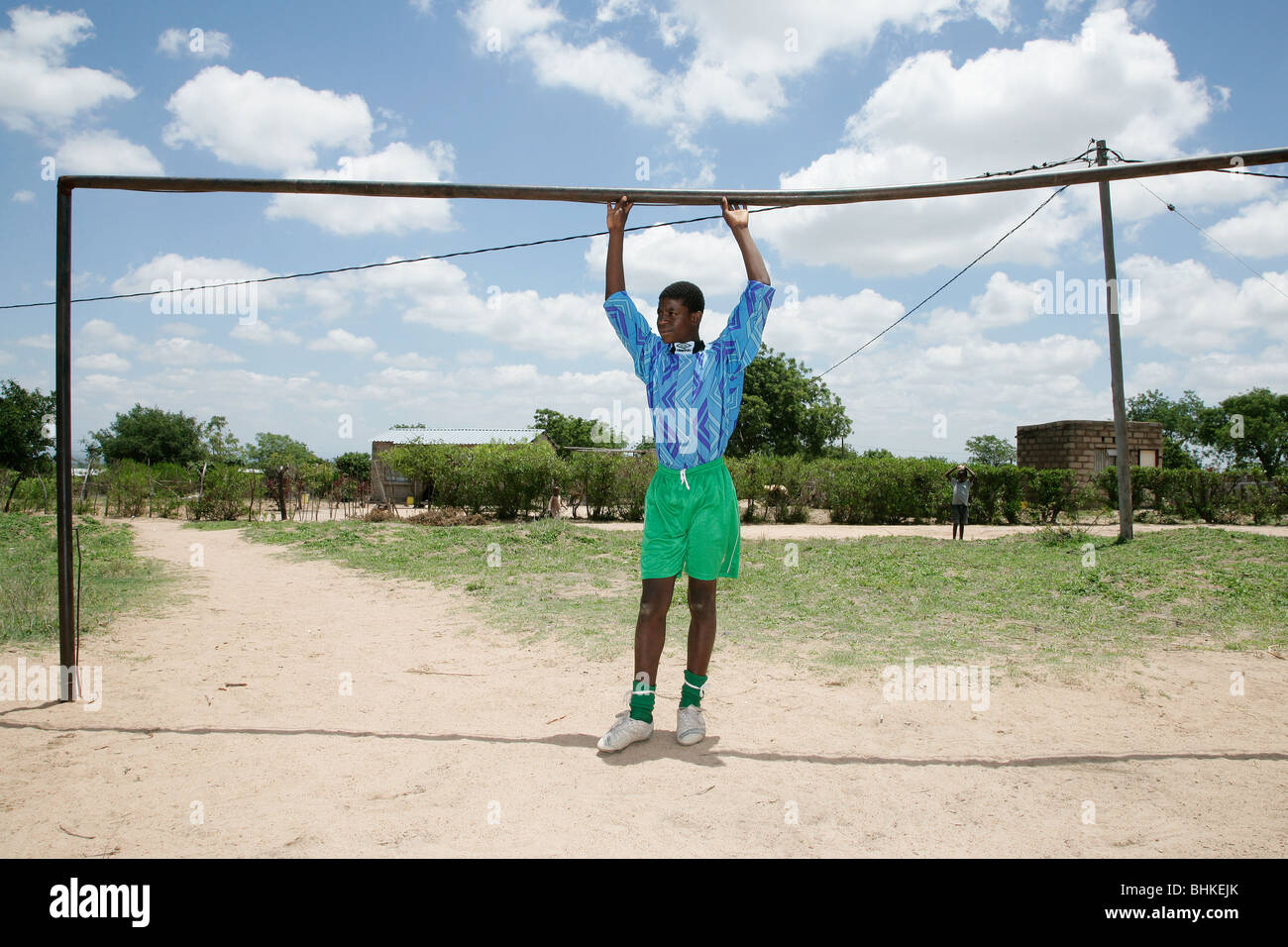 A young, black South African boy standing in a soccer goal mouth with his hands touching the cross bar on the school football Stock Photo