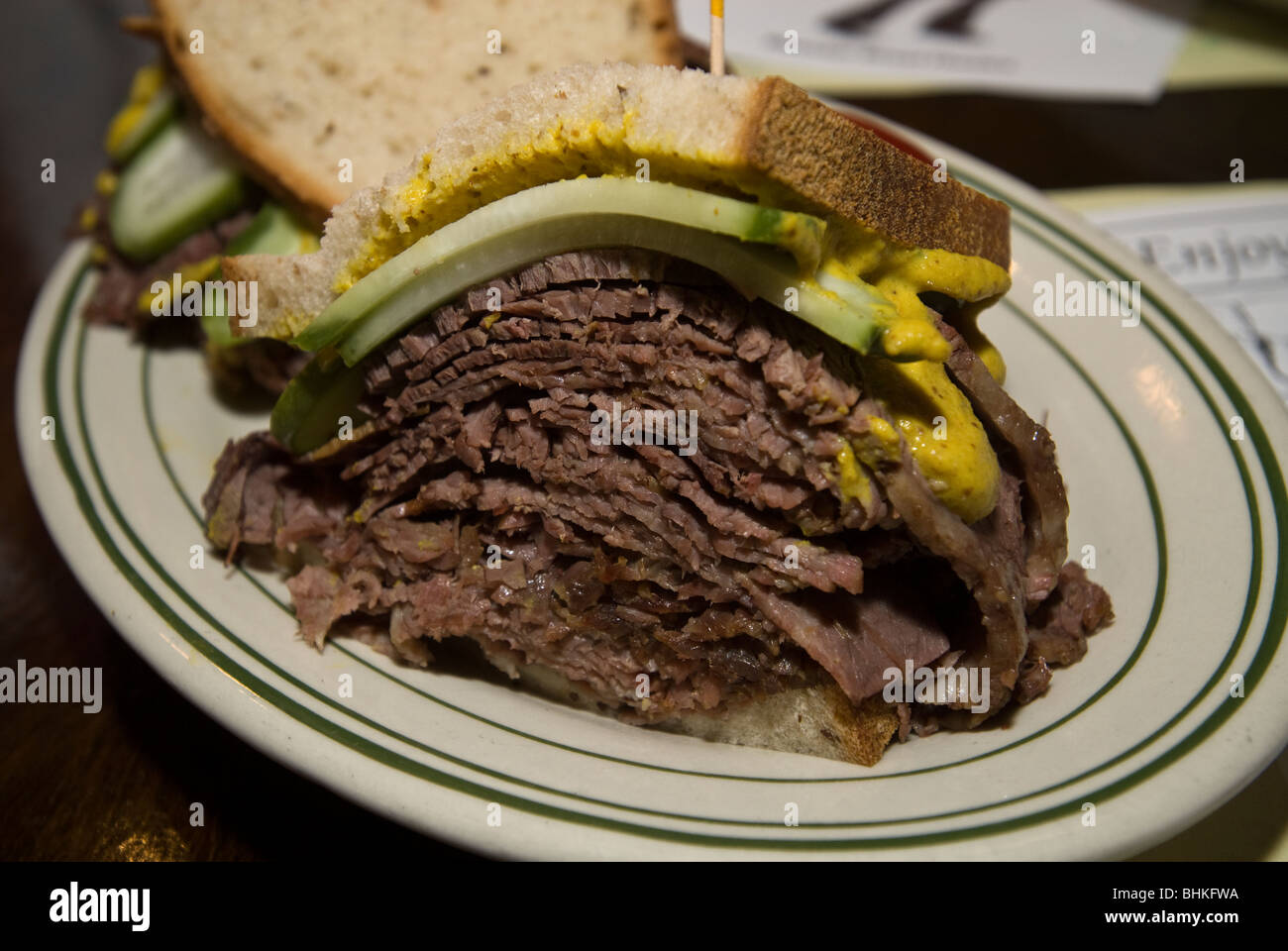 A sliced brisket, chopped liver, pickle, cole slaw on rye sandwich at