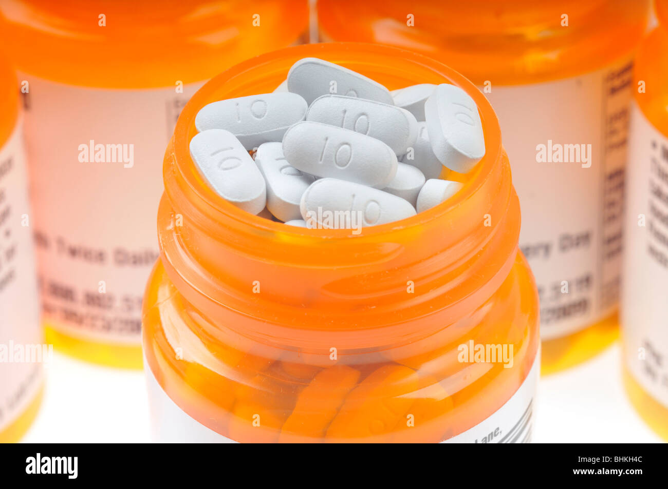 Open prescription bottle of tablets of the drug Namenda surrounded by  more prescription bottles on white background. Stock Photo